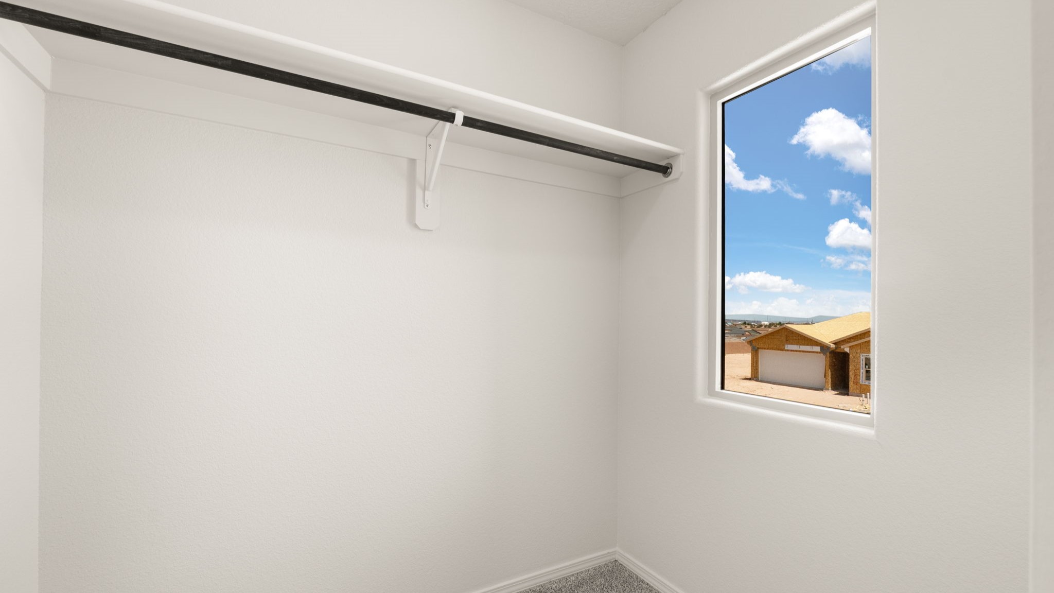 Walk in closet with a hanging rod.