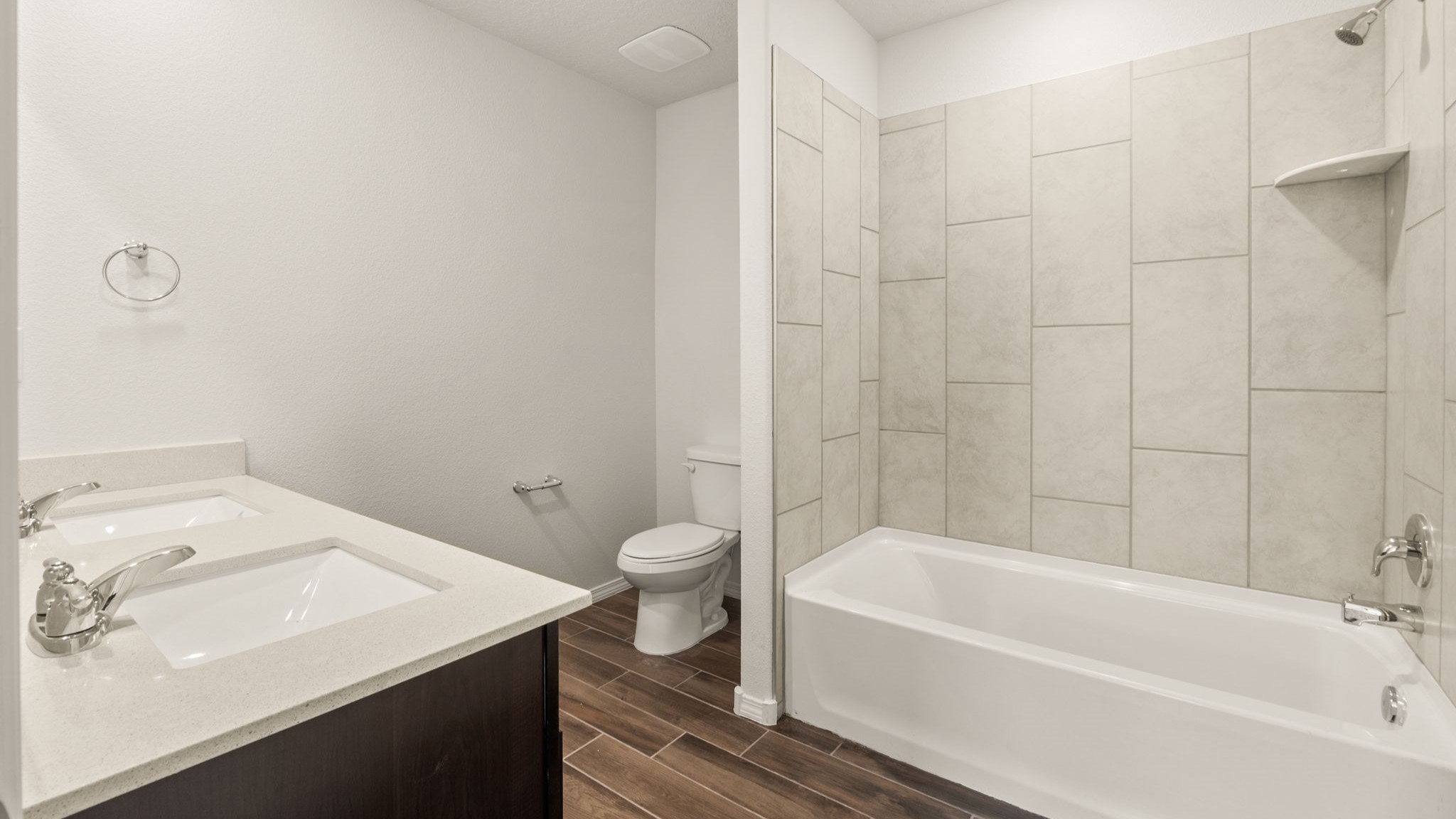 Bathroom with dual sinks, toilet, and shower tub.