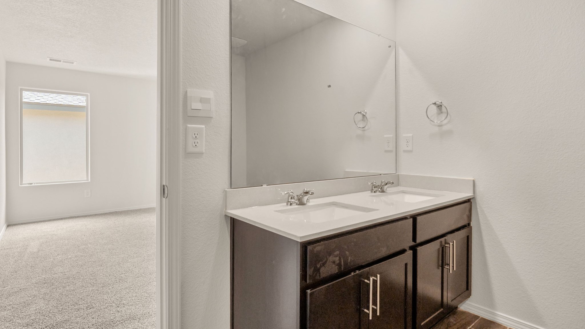Bathroom with dual sinks, a white countertop, and brown cabinets.