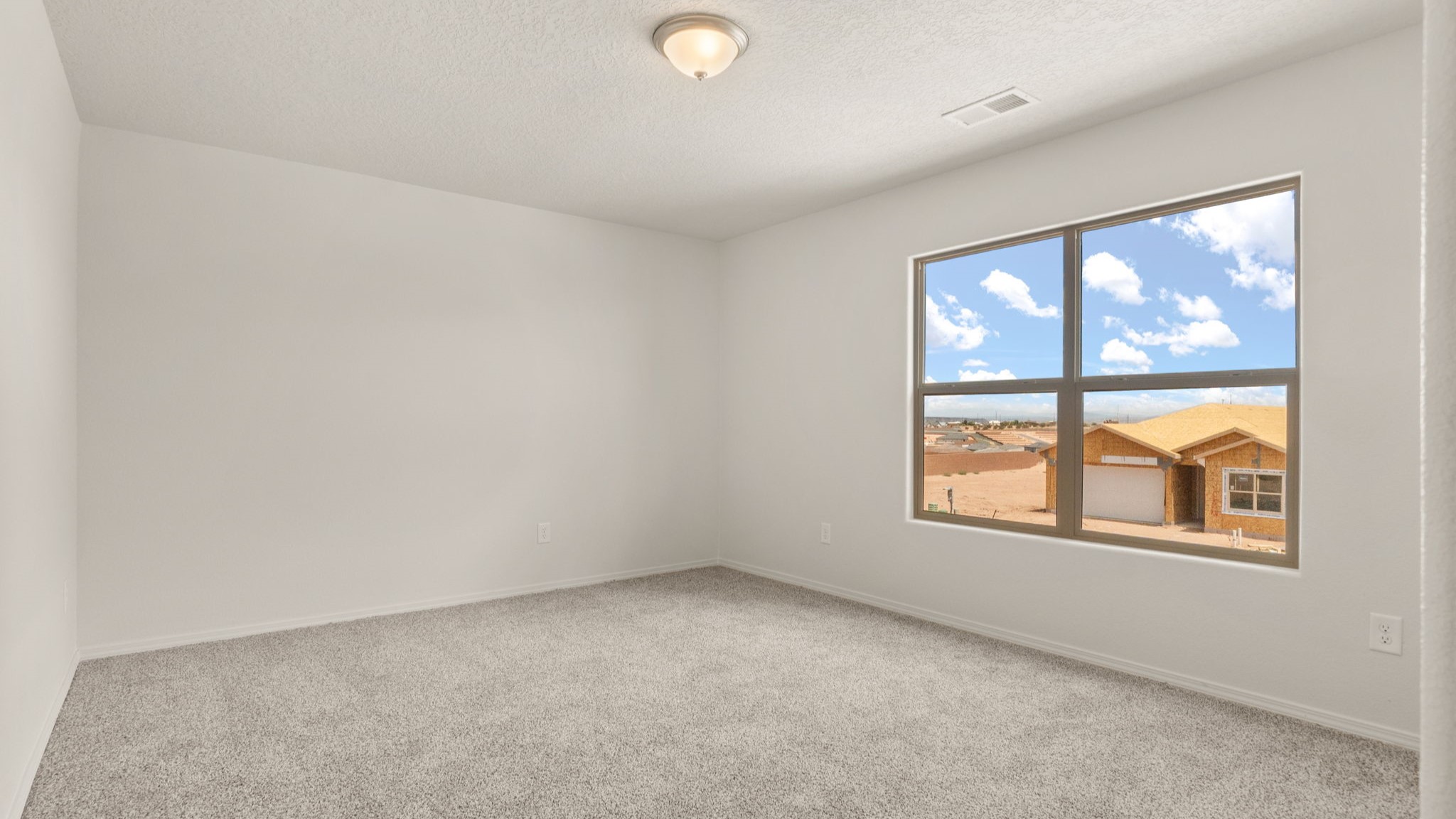 Bedroom with brown carpet, white walls, and a window.