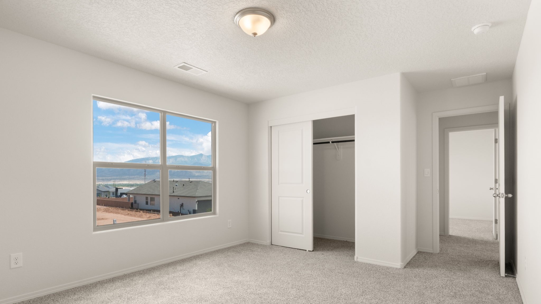 Bedroom with brown carpet, white walls, and a window.