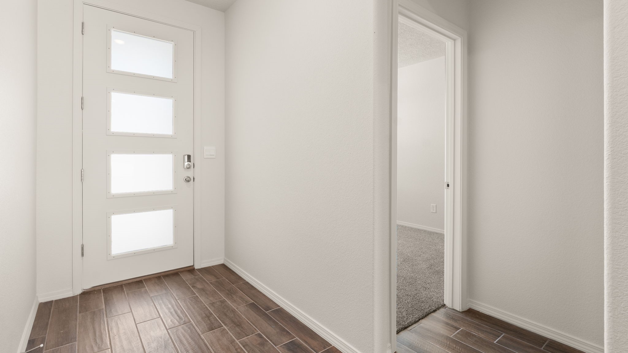 Entryway with brown wood flooring and white walls.