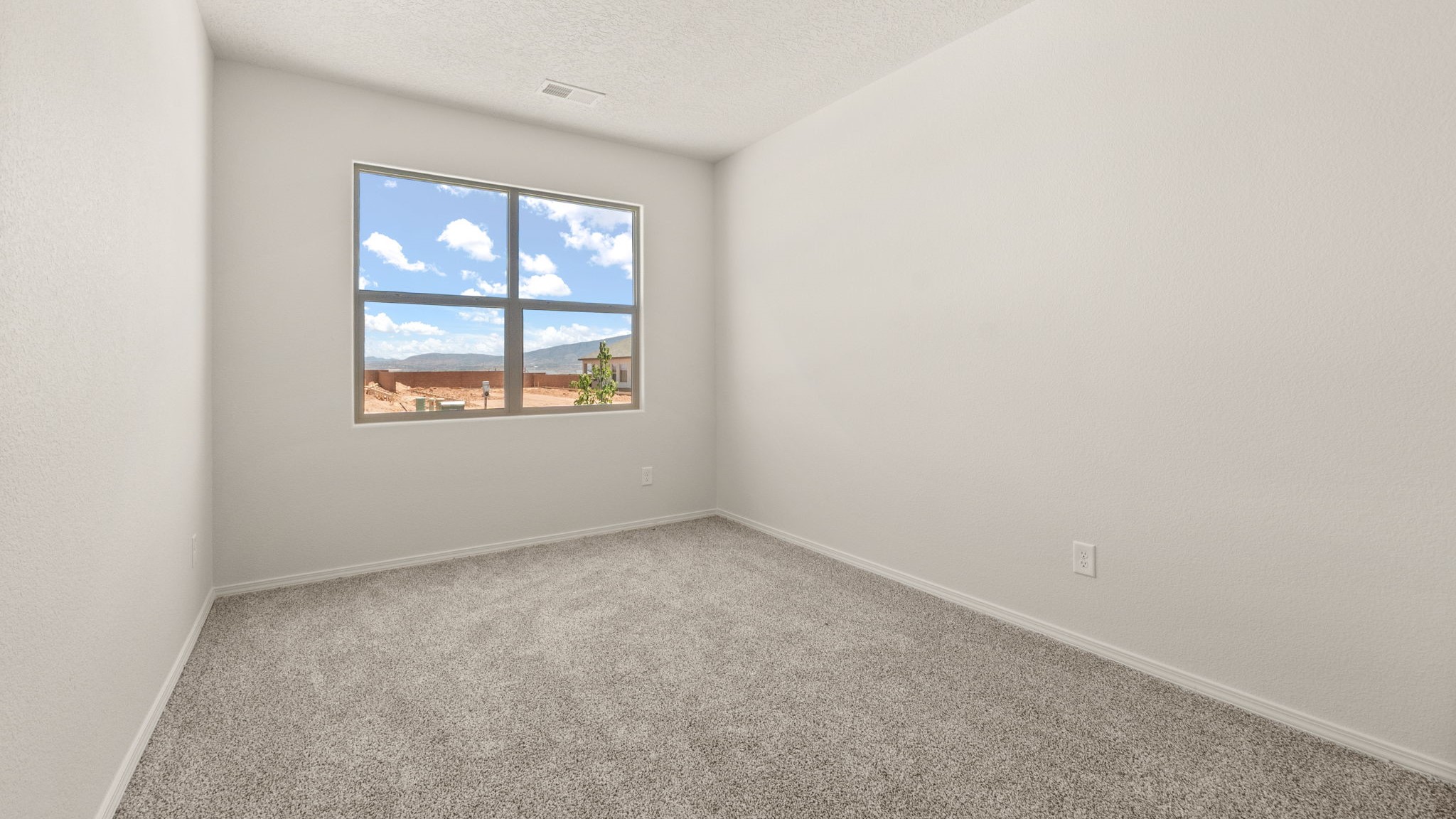 Bedroom with brown carpet, white walls, and a window.