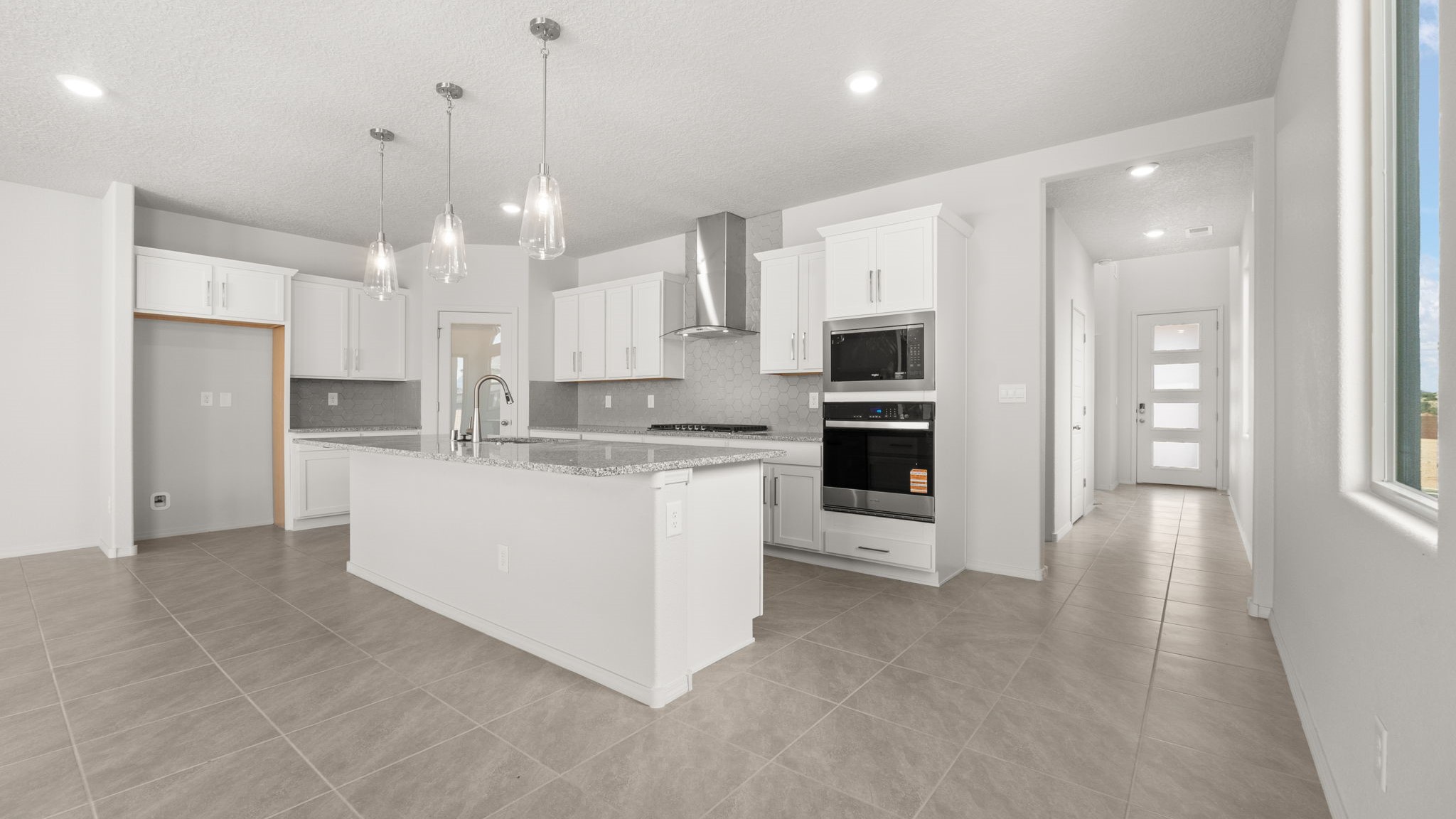 Kitchen with white cabinets, stainless steel appliances, and white and grey countertops.