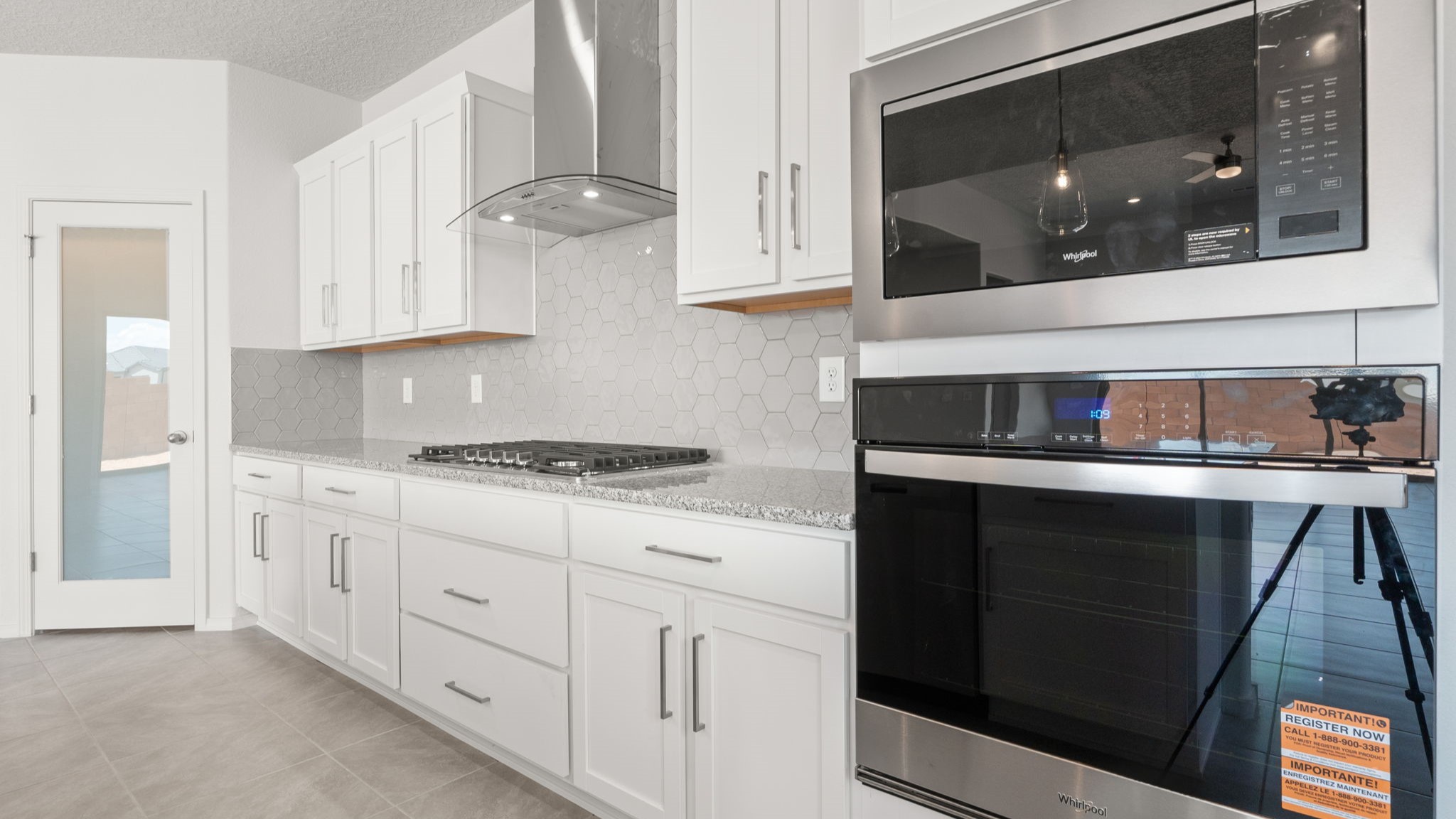Kitchen with white cabinets, stainless steel appliances, and white and grey countertops.