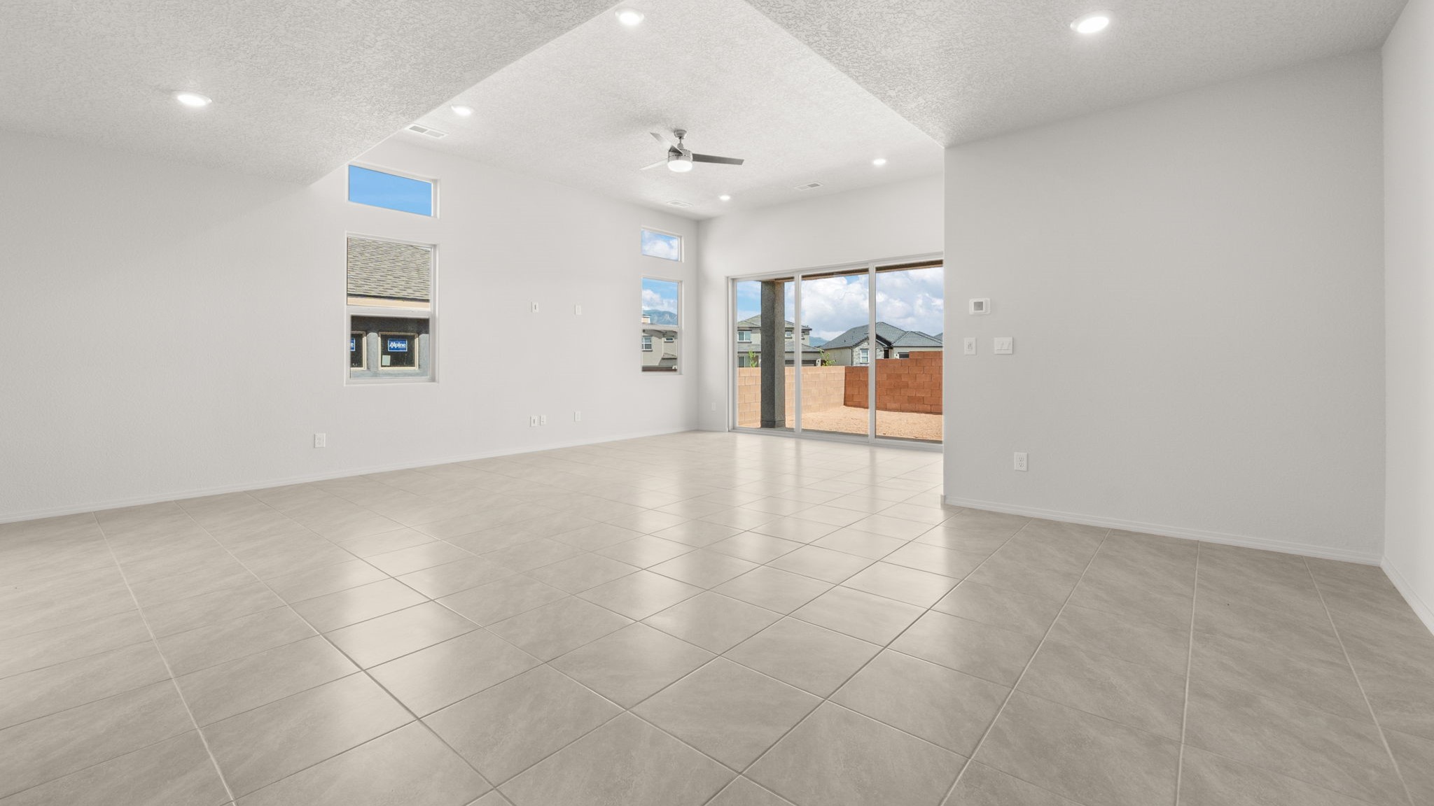 Living and dining area with white walls, light brown tile, and large windows.