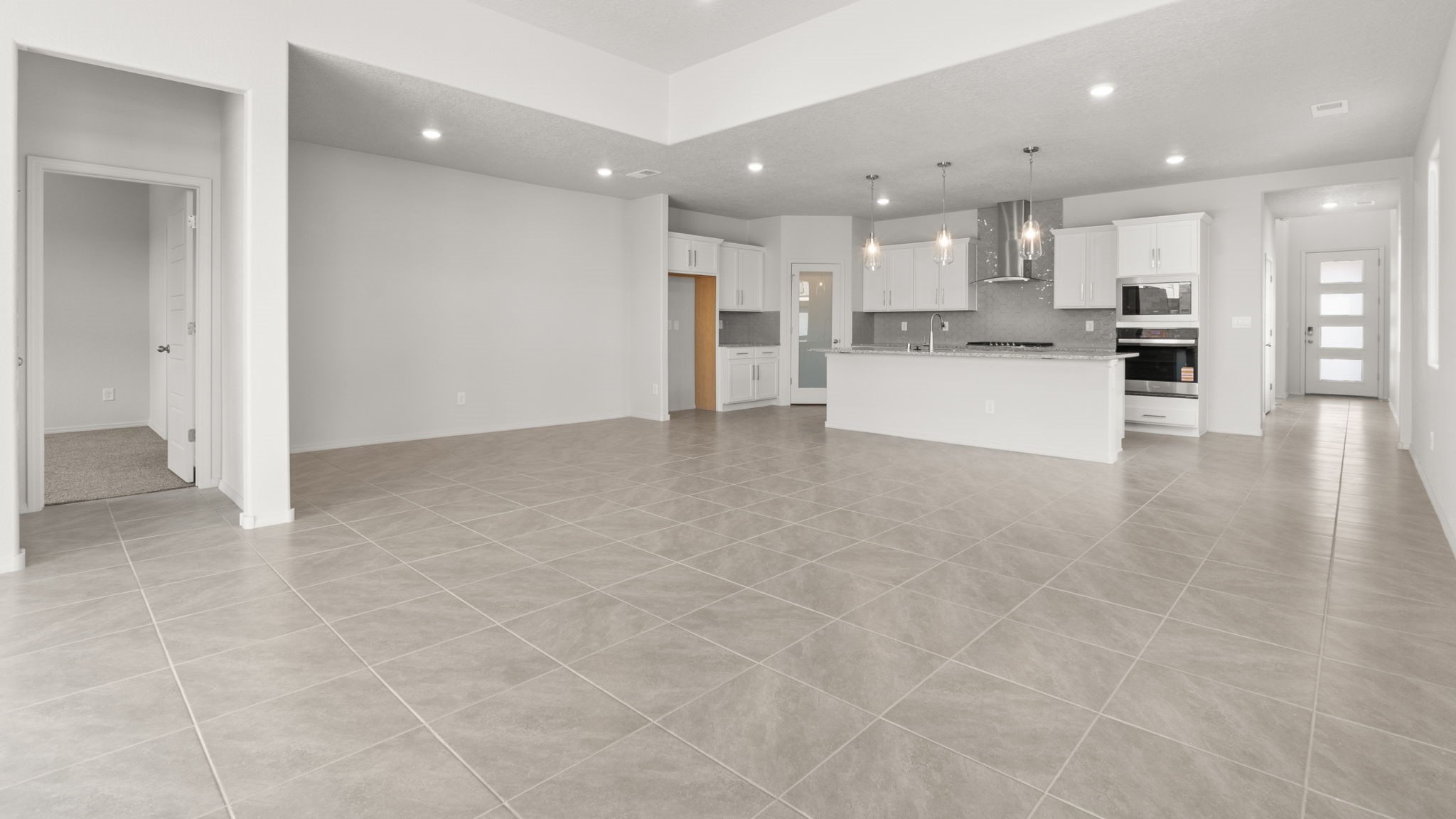 Living and dining area with white walls, light brown tile, and large windows.