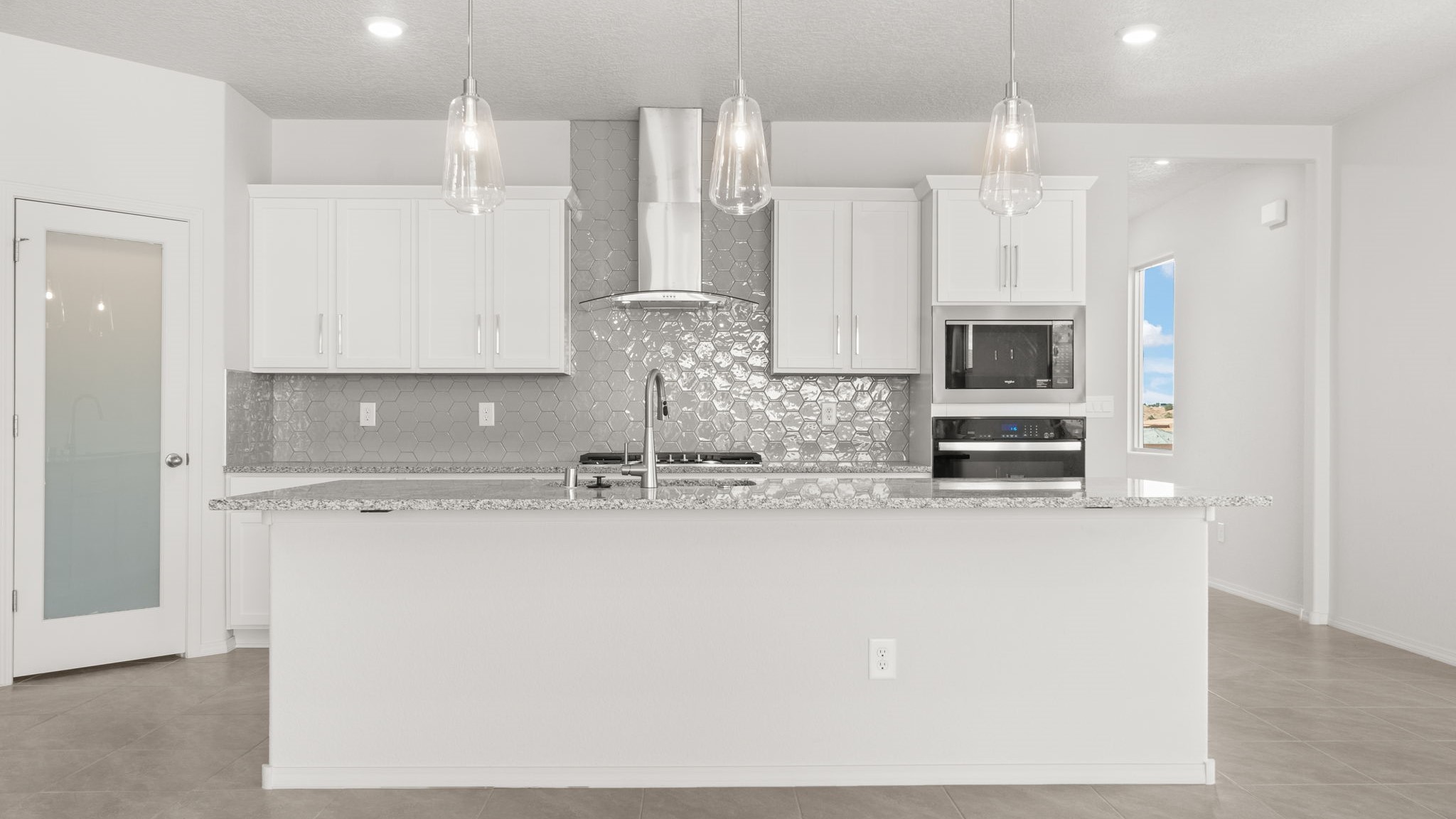 Kitchen with white cabinets, stainless steel appliances, and white and grey countertops.