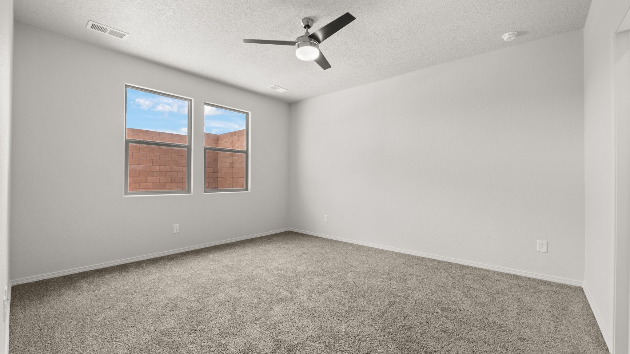 Bedroom with white walls and light brown carpet.
