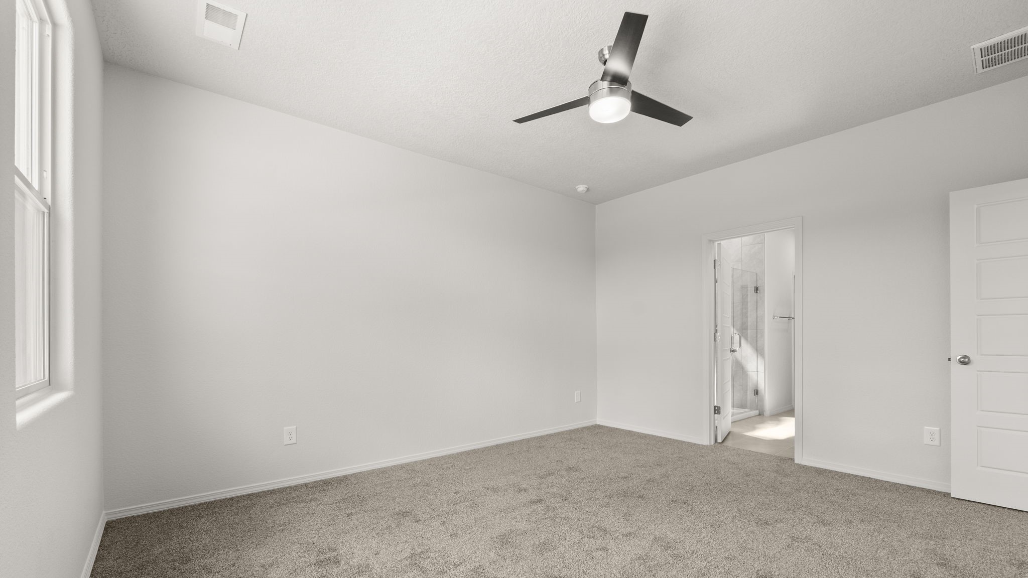 Bedroom with white walls and light brown carpet.