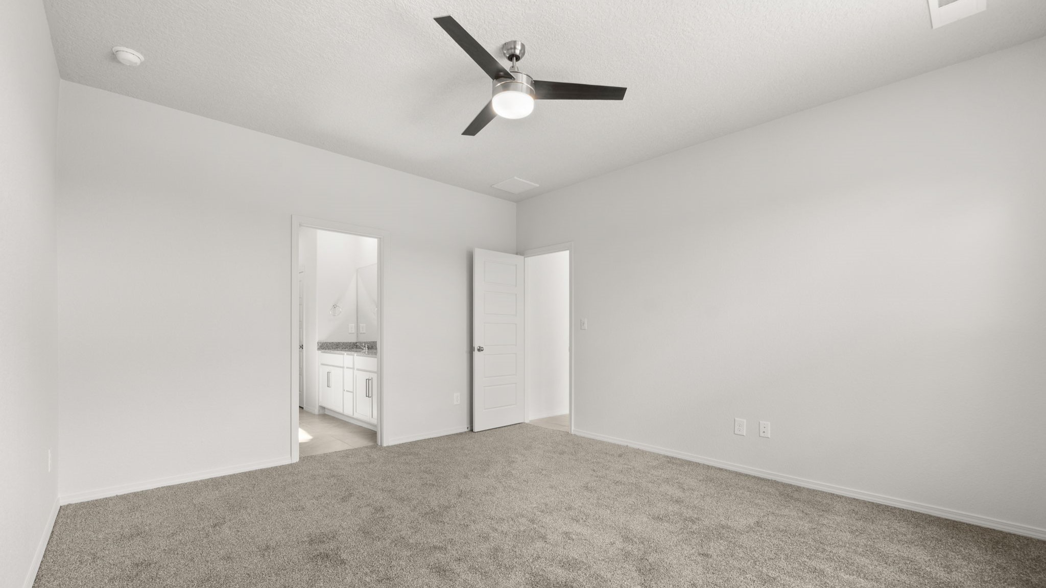 Bedroom with white walls and light brown carpet.
