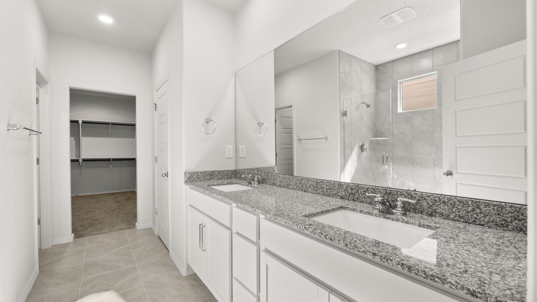 Bathroom featuring dual sinks and a walk in closet.