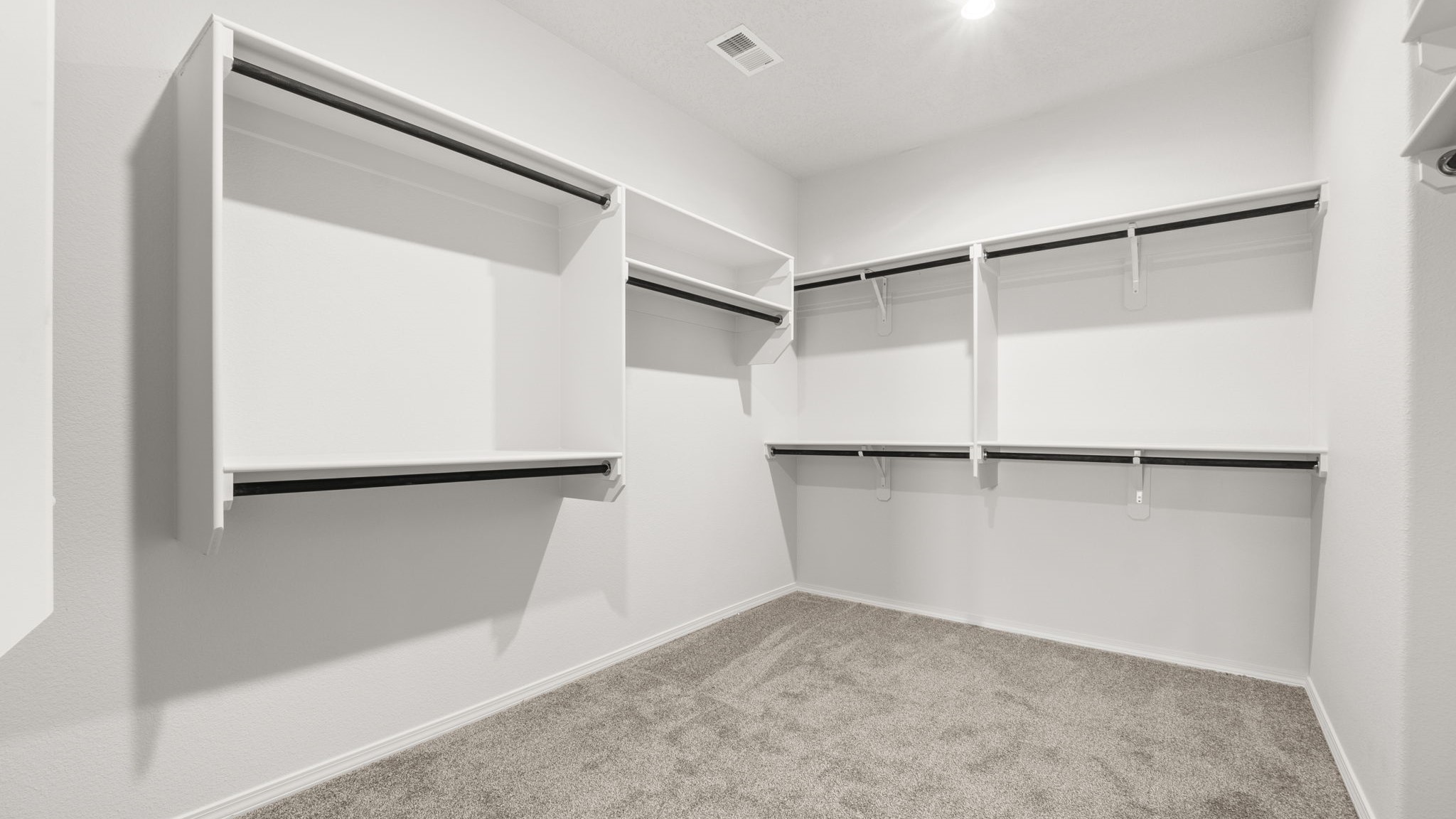 Walk in closet with built in shelving and hanging rods.