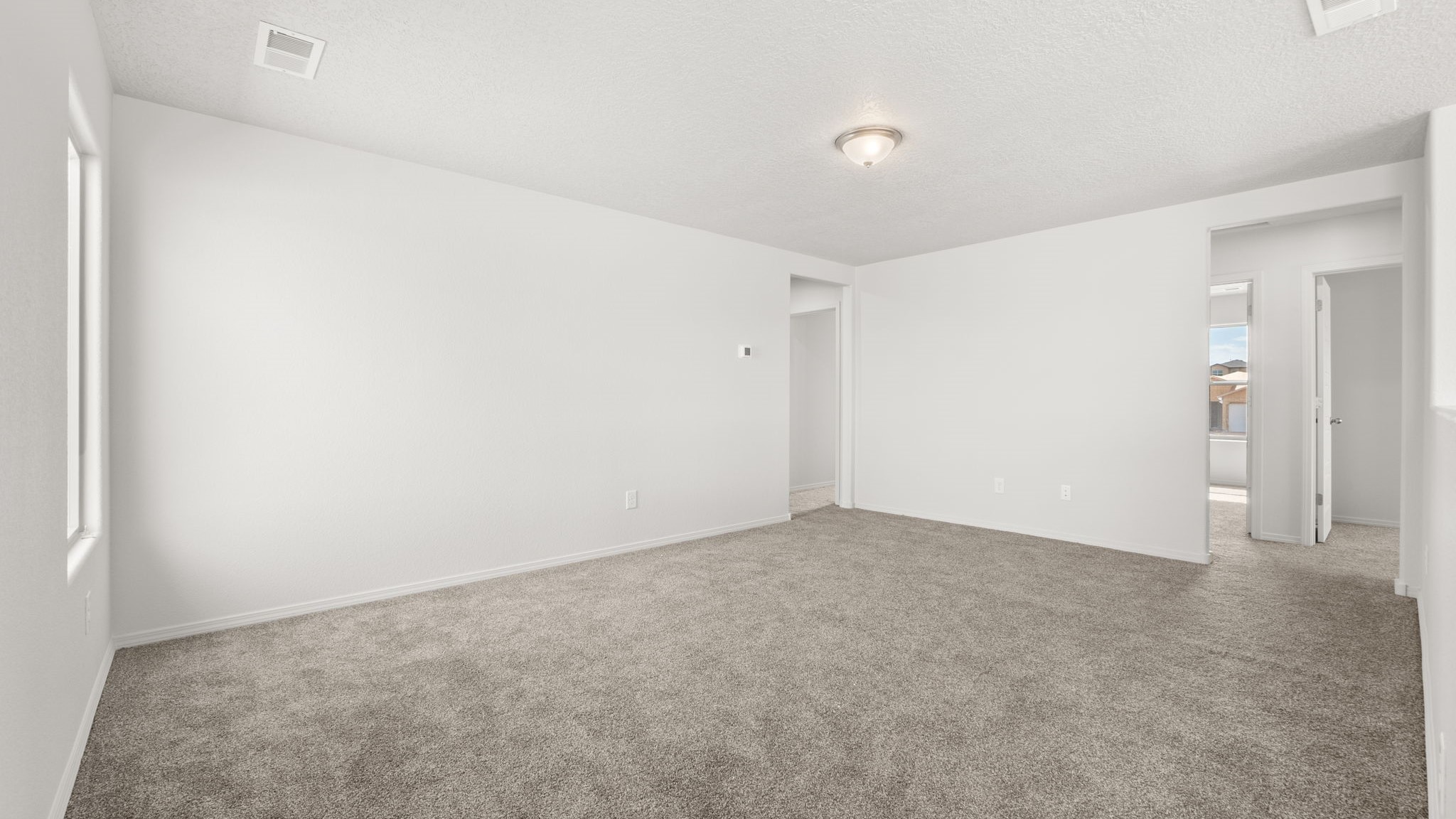 Landing at the top of the stairs with white walls, brown carpet, and large windows.