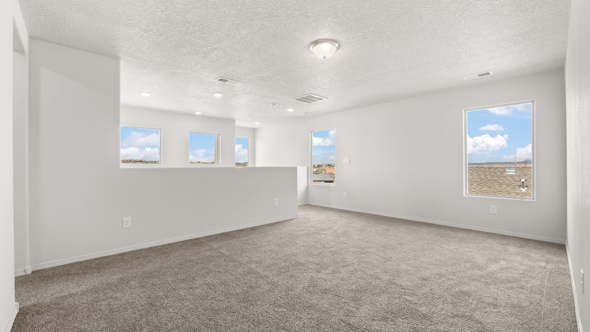 Landing at the top of the stairs with white walls, brown carpet, and large windows.