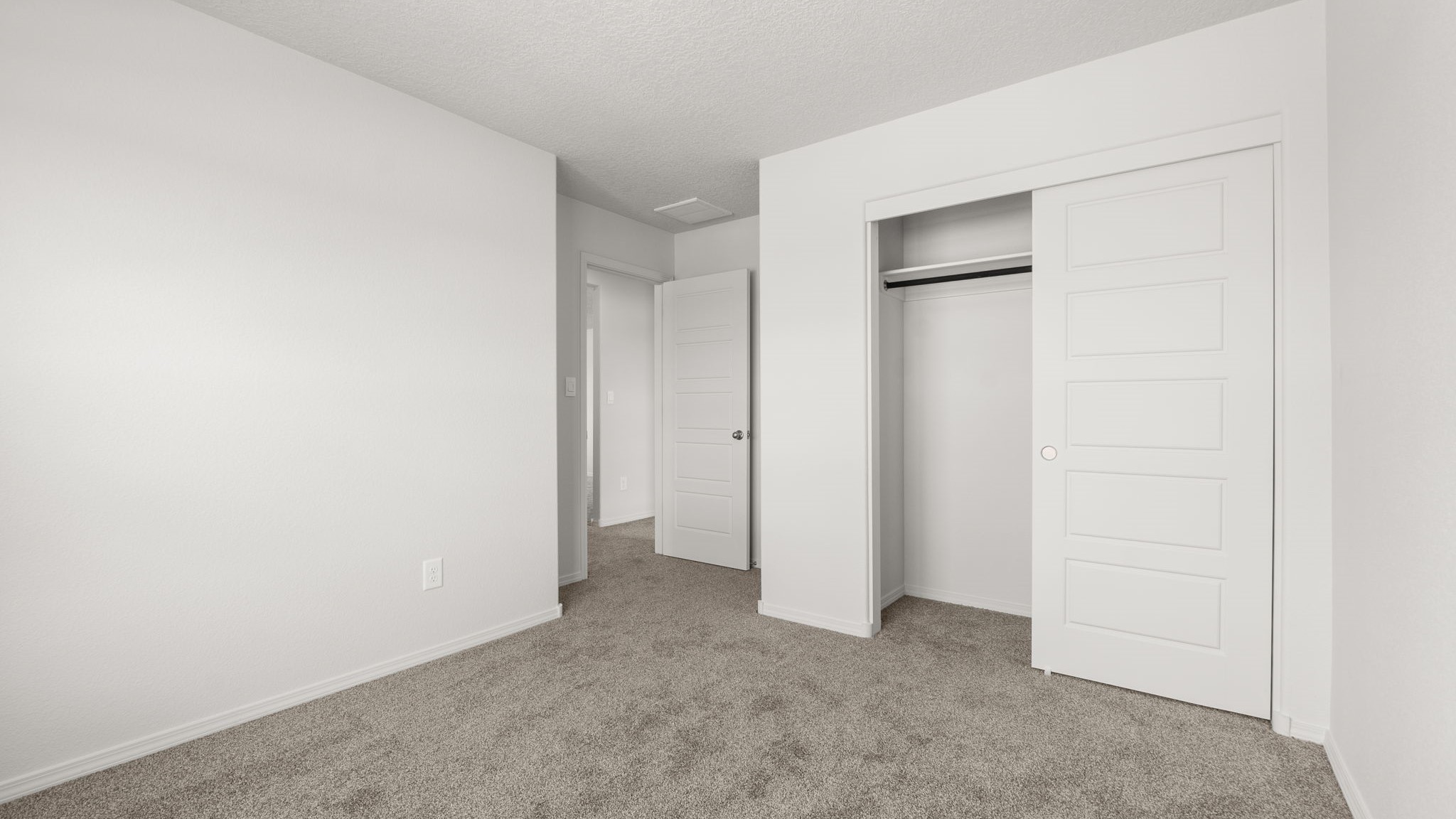 Bedroom with white walls, brown carpet, and a closet.