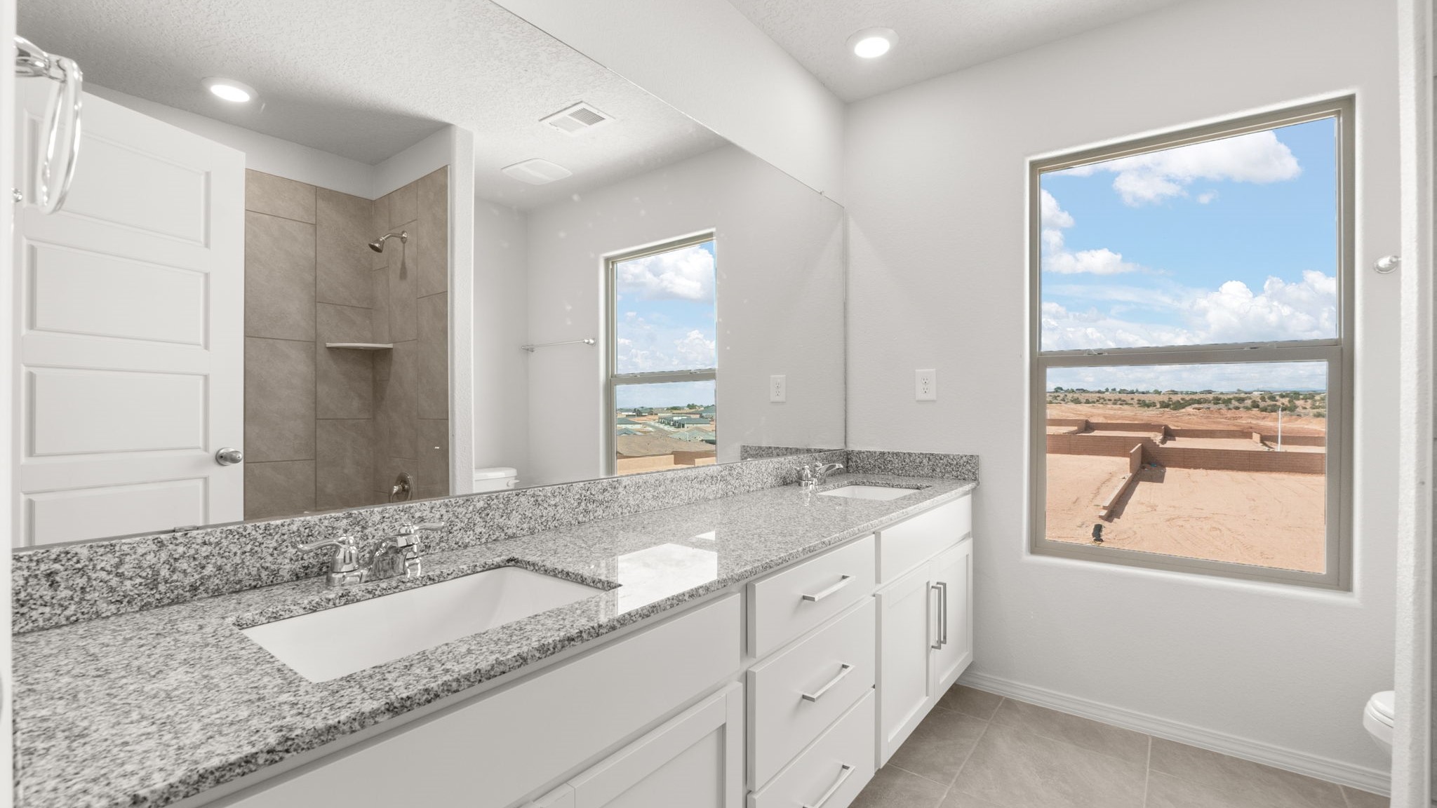 Bathroom with dual sinks, a toilet, and a shower.
