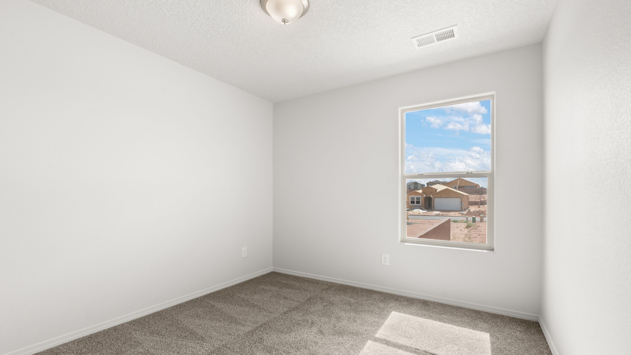 Bedroom with white walls, brown carpet, and a large window.