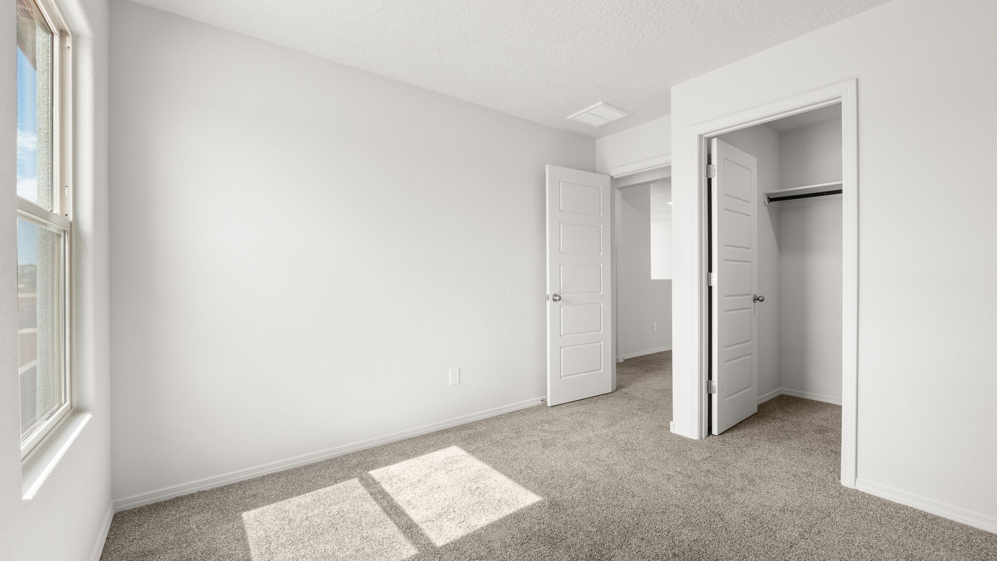 Bedroom with white walls, brown carpet, and a closet.