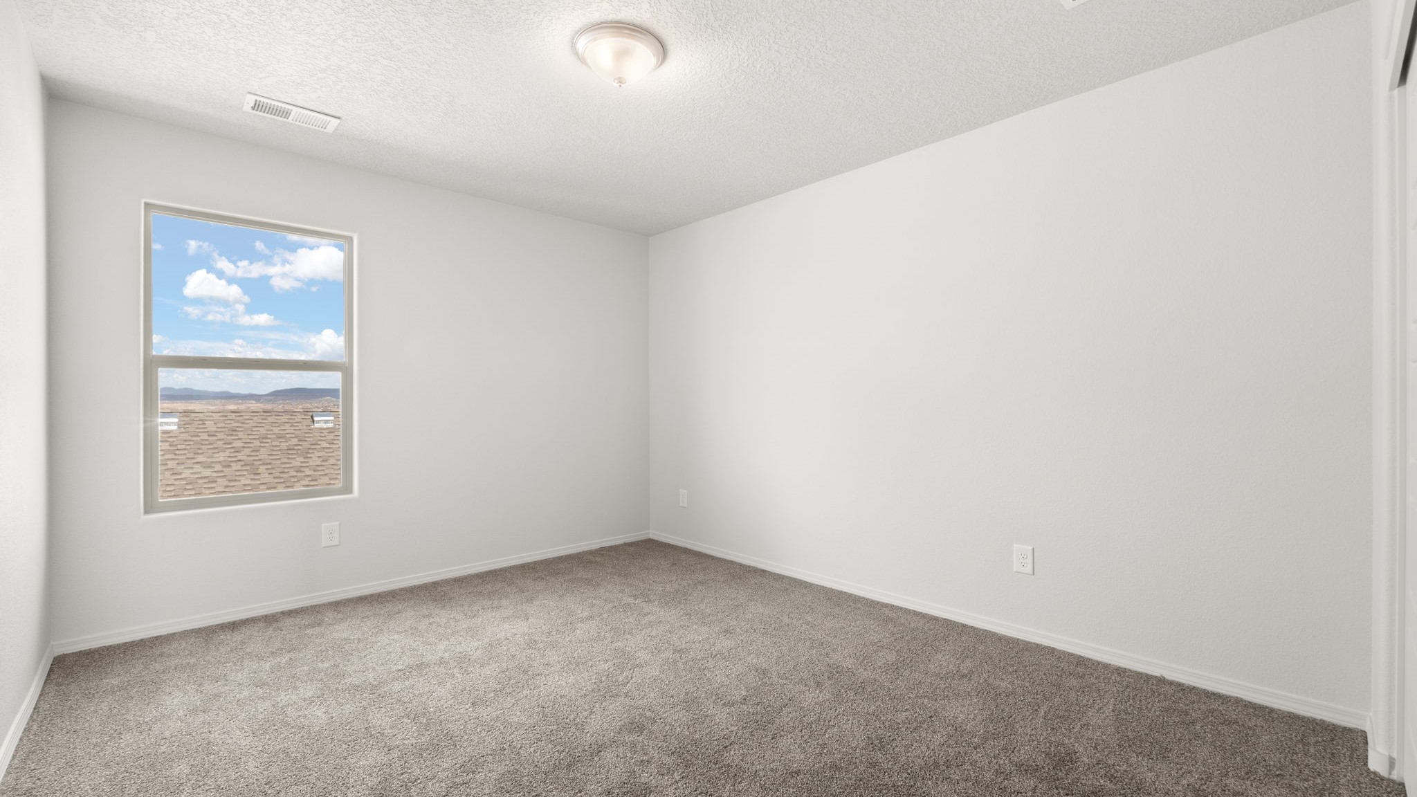 Bedroom with white walls, brown carpet, and a large window.