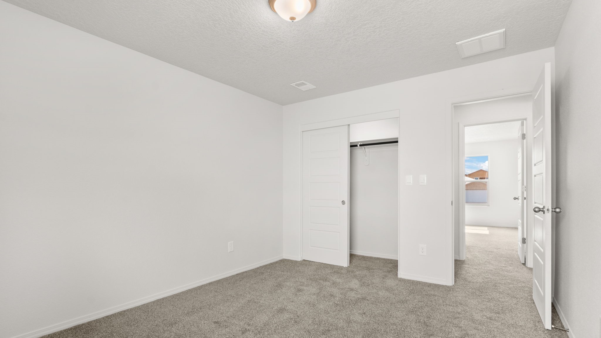 Bedroom with white walls, brown carpet, and a closet.
