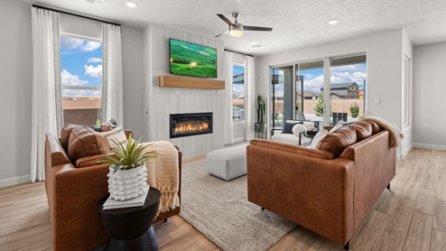 The destin living room with tile floors, modern rectangle fireplace, with sliding glass door leading to the backyard and covered patio.