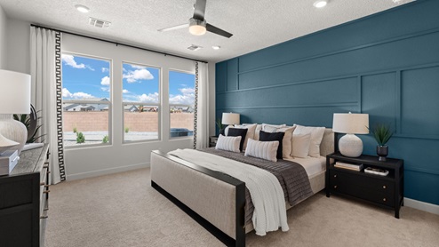 The destin primary suite with 3 large panel windows, carpet flooring, and ceiling fan.