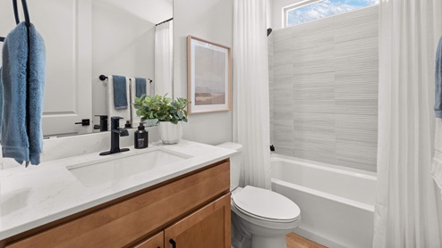 Bathroom 2 with storage shelves, single vanity sink, and tub shower combo, with tile surrounds.