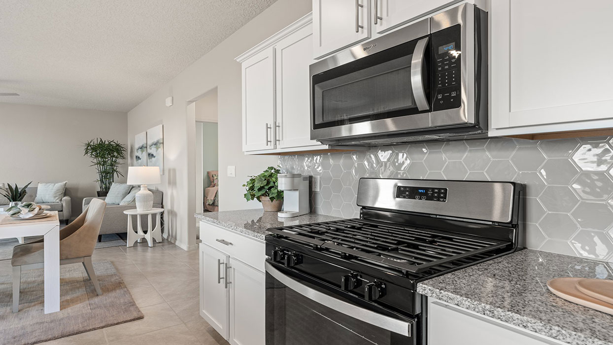 Kitchen island with sink and appliance suite included providing prep space and seating at Los Diamantes Phase III