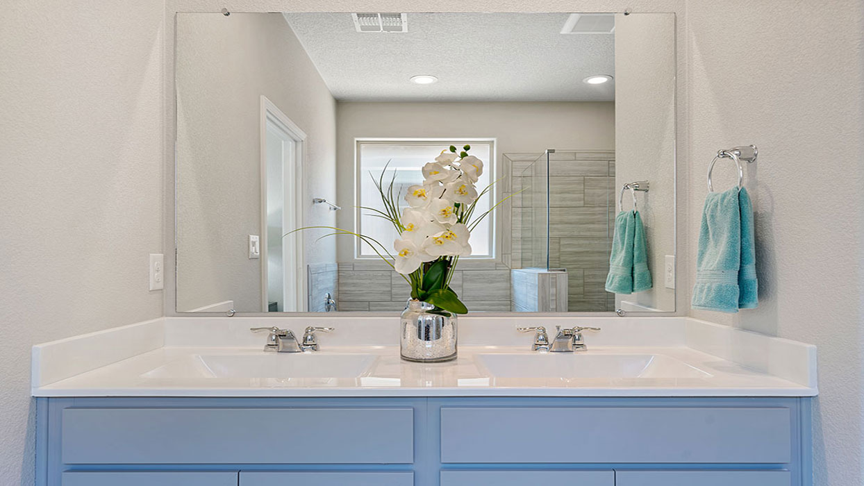 Vanity with two sinks, framed mirror, and polished new fixtures at Los Diamantes Phase III