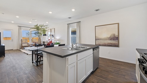 Different view of the kitchen island open concept view of the dining and living area and glass back door.