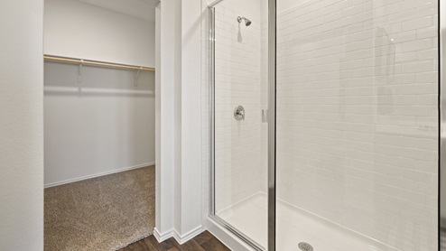 Primary bathroom with tile walk in shower, bright light fixtures, and with built in shelves.