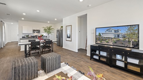 A spacious open floor plan living room and kitchen area with hardwood floors, and trey ceilings.