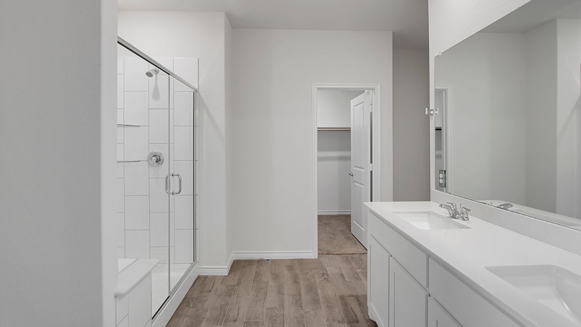 The primary suite includes a luxurious en-suite bathroom with a walk-in shower, glass enclosure, bench, double vanity sinks, and a private toilet room.