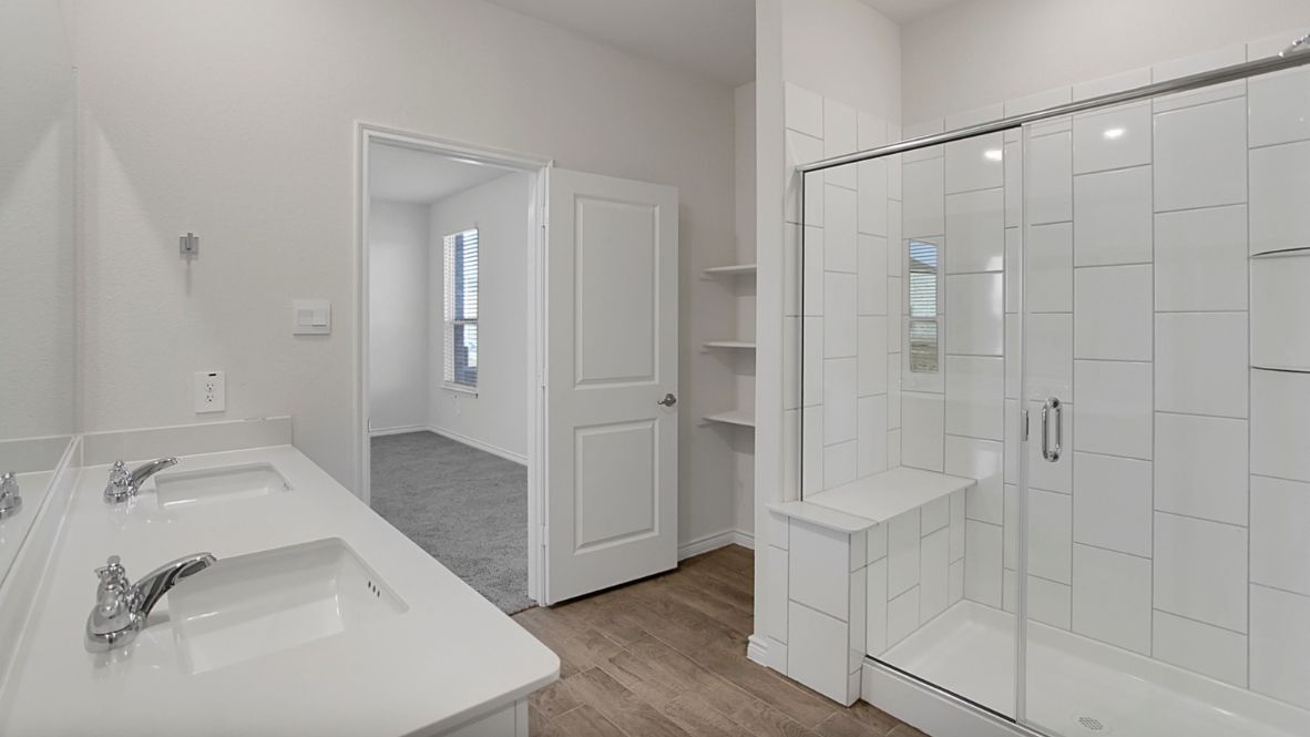 The primary suite includes a luxurious en-suite bathroom with a walk-in shower, glass enclosure, bench, double vanity sinks, and a private toilet room.