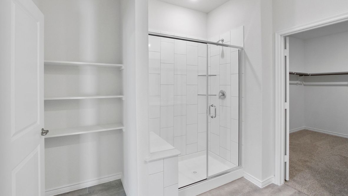 Spacious modern bathroom featuring a glass-enclosed shower, a large soaking tub with tiled surround and dual-sink vanity with sleek countertop. The layout includes a private water closet and a walk-in closet for added convenience, with natural light streaming through the window.