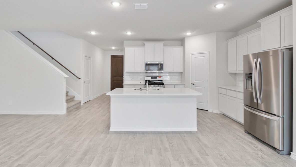 Modern kitchen with white cabinetry, quartz countertops, stainless steel appliances, and a subway tile backsplash