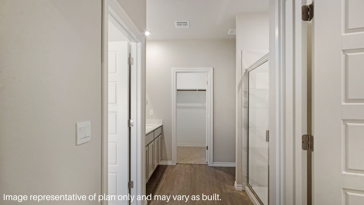 The primary bedroom can be entered through the family room. This bedroom features carpet floors and two bright windows, allowing for sunlight to adorn the room with its rays. The primary bedroom opens to the primary bathroom, complete with vinyl floors, a standing shower, a double sink, and a separate toilet room. The two carpeted walk-in closets on each side of the bathroom provide more than enough room for storage.