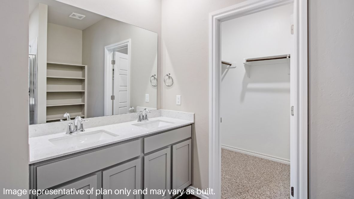 The primary bedroom can be entered through the family room. This bedroom features carpet floors and two bright windows, allowing for sunlight to adorn the room with its rays. The primary bedroom opens to the primary bathroom, complete with vinyl floors, a standing shower, a double sink, and a separate toilet room. The two carpeted walk-in closets on each side of the bathroom provide more than enough room for storage.