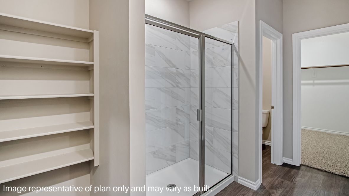 The primary bedroom can be entered through the family room. This bedroom features carpet floors and two bright windows, allowing for sunlight to adorn the room with its rays. The primary bedroom opens to the primary bathroom, complete with vinyl floors, a standing shower, a double sink, and a separate toilet room. The two carpeted walk-in closets on each side of the bathroom provide more than enough room for storage.