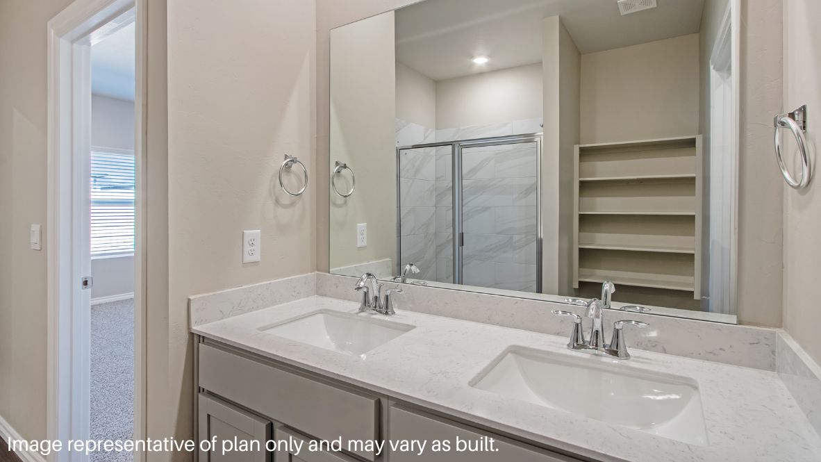 The primary bedroom can be entered through the family room. This bedroom features carpet floors and two bright windows, allowing for sunlight to adorn the room with its rays. The primary bedroom opens to the primary bathroom, complete with vinyl floors, a standing shower, a double sink, and a separate toilet room. The two carpeted walk-in closets on each side of the bathroom provide more than enough room for storage.