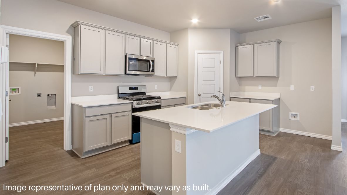 Continuing through the foyer, you will find the powder room, which is finished with vinyl flooring, and the carpeted stairway. The family room, dining room, and L-shaped kitchen are just beyond the staircase. This open concept living and dining space makes this house perfect for hosting football celebrations or large family gatherings. The vinyl flooring and bright windows allow the room to glow with natural lighting. The L-shaped kitchen is equipped with stainless-steel appliances, a large kitchen island, and a tall pantry. The utility room, which has vinyl flooring and space for a washer and dryer, can be accessed through the kitchen.