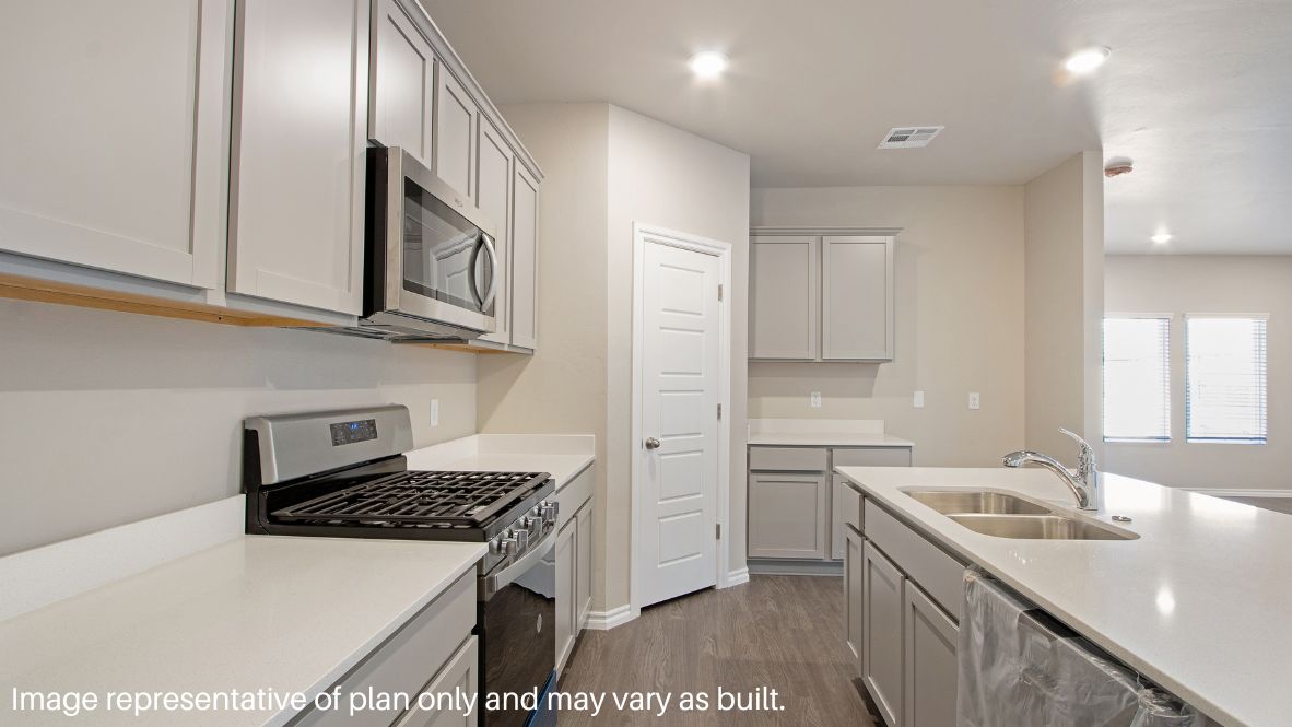 Continuing through the foyer, you will find the powder room, which is finished with vinyl flooring, and the carpeted stairway. The family room, dining room, and L-shaped kitchen are just beyond the staircase. This open concept living and dining space makes this house perfect for hosting football celebrations or large family gatherings. The vinyl flooring and bright windows allow the room to glow with natural lighting. The L-shaped kitchen is equipped with stainless-steel appliances, a large kitchen island, and a tall pantry. The utility room, which has vinyl flooring and space for a washer and dryer, can be accessed through the kitchen.