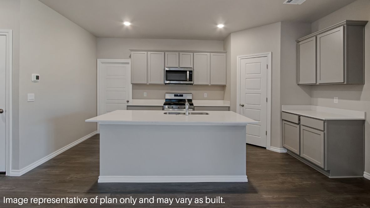 Continuing through the foyer, you will find the powder room, which is finished with vinyl flooring, and the carpeted stairway. The family room, dining room, and L-shaped kitchen are just beyond the staircase. This open concept living and dining space makes this house perfect for hosting football celebrations or large family gatherings. The vinyl flooring and bright windows allow the room to glow with natural lighting. The L-shaped kitchen is equipped with stainless-steel appliances, a large kitchen island, and a tall pantry. The utility room, which has vinyl flooring and space for a washer and dryer, can be accessed through the kitchen.