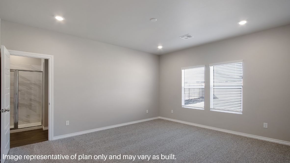 The primary bedroom can be entered through the family room. This bedroom features carpet floors and two bright windows, allowing for sunlight to adorn the room with its rays. The primary bedroom opens to the primary bathroom, complete with vinyl floors, a standing shower, a double sink, and a separate toilet room. The two carpeted walk-in closets on each side of the bathroom provide more than enough room for storage.