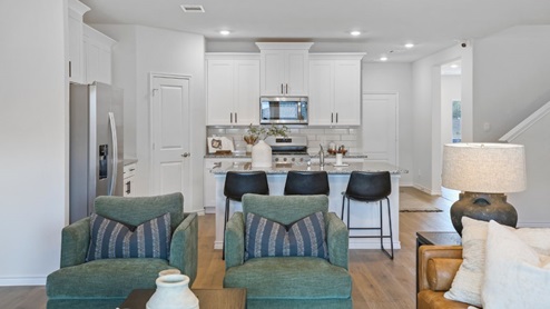 Spacious living room with brown flooring, white walls and windows