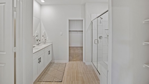 bathroom with dual vanity sinks, toilet, and a walk in shower