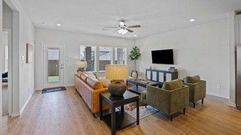Spacious living room with brown flooring, white walls and windows