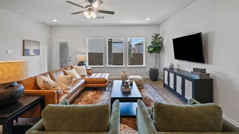 Spacious living room with brown flooring, white walls and windows