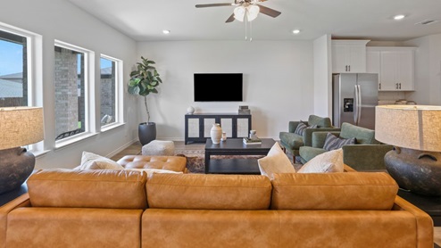 Spacious living room with brown flooring, white walls and windows